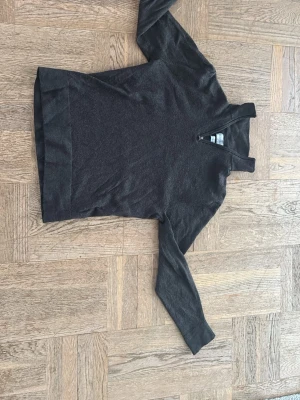 Mörkbrun stickad tröja med halvzip - Mysig mörkbrun stickad tröja från These Glory Days med halvzip framtill. Tröjan har lång ärm och hög krage, perfekt för lager-på-lager. Materialet känns mjukt och passar bra till både jeans och chinos.