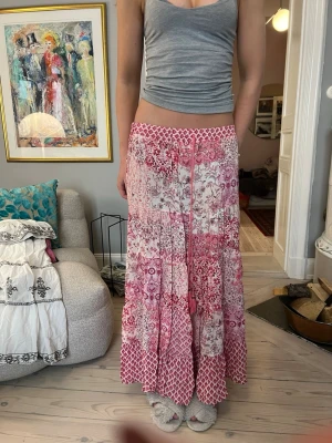 Rosa och vit långkjol från zara - Långkjol i rosa och vitt med blandade mönster och snörning i midjan. Kjolen har volangdetaljer och ett bohemiskt uttryck med olika nyanser av rosa och vitt. Perfekt för dig till sommaren 