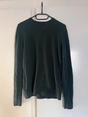 Mörkgrön stickad tröja Samsøe Samsøe - Mörkgrön stickad tröja från Samsøe Samsøe med rund halsringning och långa ärmar. Tröjan har ribbade muddar vid ärmslut och nederkant, och är tillverkad i ett mjukt, tunt stickat material som passar perfekt till lager på lager.