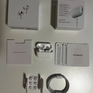 Apple AirPods Pro 2 trådlösa hörlurar - Säljer ett par vita Apple AirPods Pro 2 med laddningsetui. Hörlurarna har en stilren och kompakt design med silikonpluggar för bästa passform. Levereras med originalkartong, extra öronproppar och laddningskabel. Perfekta för musik, samtal och träning.
