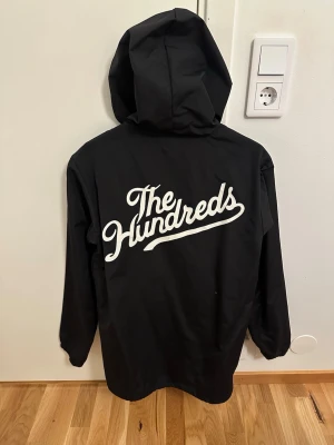 The Hundreds Jacka - Coach / vind / regnjacka med luva från The Hundrades.  Knappt använd något alls dock blivit lite färgsläpp i luvan som syns på sista bilden. I övrigt väldigt fint skick.  Storlek M