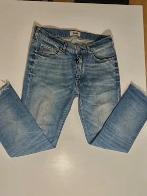 Ljusblå jeans från Acne Studios - Snygga ljusblå jeans från Acne Studios med klassisk femficksmodell och råa, fransiga benslut. Jeansen har en rak passform och är tillverkade i denim med lätt tvättad look. Jeansen är köpte för 2100 men passade inte, då är priset inte hugget i sten, de är ett par unika jeans som har en straught modell och de är av klippte eller designade så de inte sitter på någon med 33 i längd. Det går att förhandla
