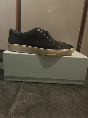 Marinblå Lanvin sneakers med lackad tå - Stilrena marinblå sneakers från Lanvin i blankt läder med vita sulor och svarta skosnören. Nypris: 4499kr. Klassisk låg modell med metallöljetter och diskret design som passar till det mesta. Perfekta för dig som gillar exklusiva och tidlösa skor. Köpte från care of Carl. Kommer med box och dustbag. PRISET ÄR EJ HUGGET I STEN.