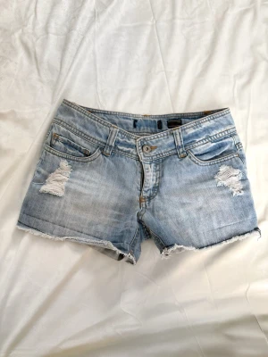 Ljusblå jeansshorts med slitningar -  Så snygga ljusblå superlågmidjade jeansshorts med slitna detaljer och råa kanter.💓 w26