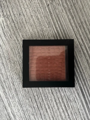 Make Up Store Blush Posh rouge - Snyggt rouge från Make Up Store i nyansen Posh. Färgen är en varm, rosabrun ton med matt finish. Kommer i en stilren, svart fyrkantig dosa med genomskinligt lock och krokodilpräglad yta på pudret. Perfekt för att ge kinderna en naturlig glow.
