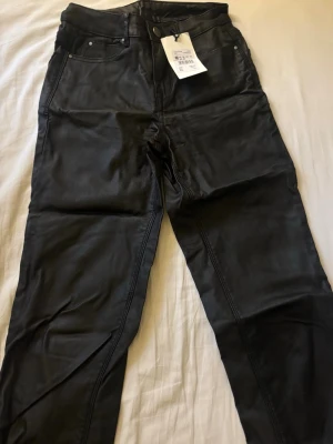 Svarta coated skinnbyxor från Vila - Säljer mina snygga svarta coated skinnbyxor från Vila med femficksmodell och hög midja. Sitter jättefint på men tyvärr för små för mig därav prislappen kvar. För fler bilder skriv gärna🩷