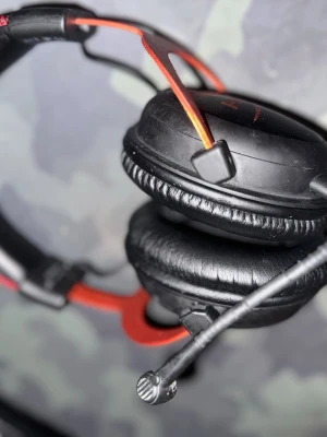 Svarta gaminghörlurar med mikrofon - Snygga svarta over-ear gaminghörlurar från HyperX med röda detaljer och justerbar mikrofon. Mjuka öronkuddar i konstläder och robust bygel för extra komfort under långa spelsessioner.