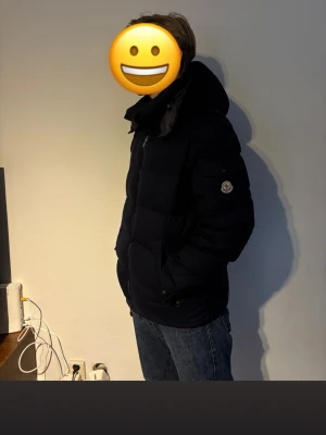 Moncler Montgenevre Flannel Down Navy - Säljer en mörkblå pufferjacka från Moncler med avtagbar huva. Jackan har en klassisk quiltad design. Liten skada på handöppningen annars så gott som ny. Storlek 5 och nypris 23 399. Modellen är 188cm och väger 85 kg.