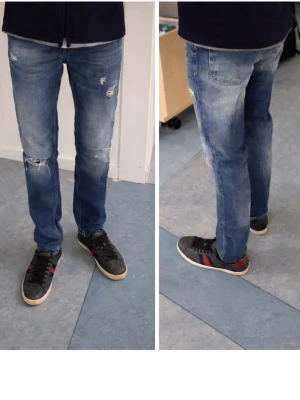 Blå slitna skinny från dondup - Säljer ett par blå skinny jeans från dondup med slitna detaljer och snygga slitningar på låren och knäna. Jeansen har klassisk femficksdesign, låg midja och är tillverkade i mjukt jeansmaterial. Perfekta för dig som gillar en trendig och avslappnad stil.