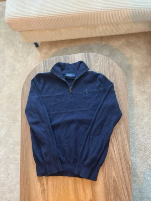 Mörkblå half-zip från Polo Ralph Lauren - Mörkblå half-zip tröja från Polo Ralph Lauren.  • Storlek: M • Passform: Regular fit • Skick: Mycket bra skick, inga hål eller fläckar • Färg: Mörkblå • Detaljer: Kort dragkedja i halsen, mjukt stickat material, ribbade muddar och nederkant samt broderad Polo-logga på bröstet  Klassisk och tidlös modell som passar perfekt till vardagsbruk och fungerar bra både över skjorta och t-shirt.  Nypris: ca 1 700–2 200 kr 