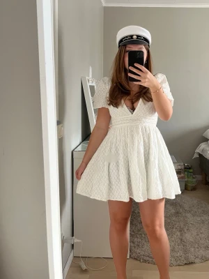 Vit kortklänning från Hello Molly - Superfin vit kortklänning från Hello Molly med djup v-ringning, puffärmar och markerad midja med en rosett man knyter där bak. perfekt för studenten 🤍 Helt ny endas testad en gång med lappen kvar, säljer då jag bestämt mig för en annan🤍original pris: 1200kr med frakt