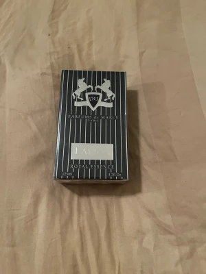 Parfums de Marly Layton EdP 125ml - Lyxig parfym från Parfums de Marly, modellen Layton Royal Essence. Flaskan rymmer 125 ml och kommer i en elegant svart förpackning med vita ränder och silverdetaljer. Doften är Eau de Parfum och tillverkad i Frankrike. Parfymen är oöppnad, alltså aldrig använd och helt ny