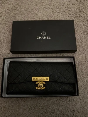 Svart plånbok  - Snygg svart plånbok  i quiltat l guldfärgade detaljer. Plånboken har en elegant rektangulär form och stängs. Perfekt för dig som gillar lyxiga accessoarer. Plånbok. #Korthållare.  