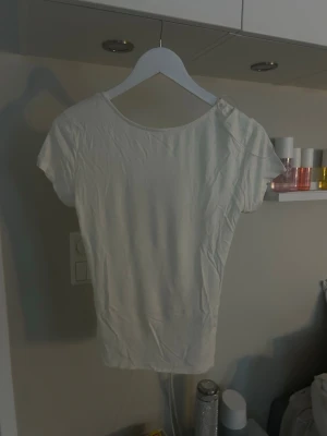 Vit topp med knyt i satin - Använd några gånger, men mest legat i garderoben. Den är i L men kan också passa S och m. Supersöt vit topp med korta ärmar och snygg knytning i satinband framtill. Toppen har en feminin, enkel design och är perfekt att styla till jeans eller kjol. Materialet känns mjukt och lätt mot huden. 🥰🥰