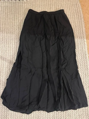 Svart midikjol med resårmidja - En svart midikjol med enkel design och resår i midjan. Kjolen är gjord i ett lätt och tunt tyg och har även fickor! 