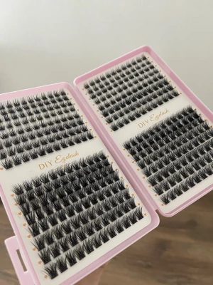 DIY individuella lösögonfransar - Säljer två askar med svarta individuella lösögonfransar för DIY-applikation. Fransarna kommer i olika längder och är organiserade i kluster för enkel applicering. Perfekt för att skapa en naturlig eller fylligare look. Förpackningen är ljusrosa och smidig att ta med.