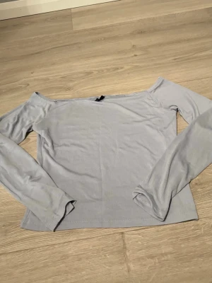 Ljusblå offshoulder topp Gina Tricot - Trendig ljusblå offshoulder topp från Gina Tricot i mjukt material. Toppen har långa ärmar och en enkel, stilren design som passar perfekt till jeans eller kjol. Perfekt för dig som gillar en clean och modern look.