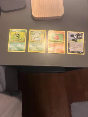 Fyra Pokémonkort blandade motiv - Säljer fyra Pokémonkort: Caterpie, Bulbasaur, Hitmonchan och Mightyena. Korten har färgstarka illustrationer och klassisk blå baksida med Pokéboll. Perfekt för samlare eller dig som vill utöka din kortlek.