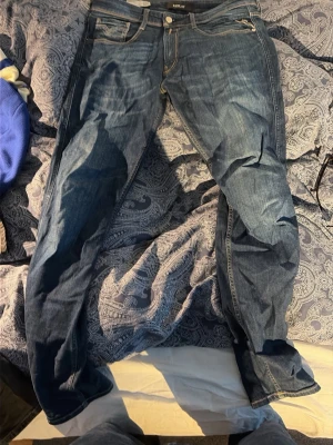 Blå jeans från Replay - Säljer ett par klassiska blå jeans från Replay med raka ben och fem fickor. Jeansen har snygga kontrastsömmar och detaljerade bakfickor. Har inget kvitto. 