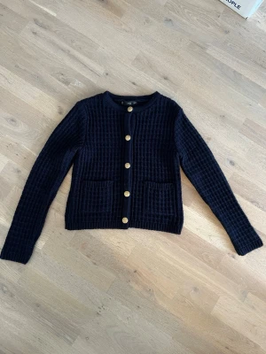 Mörkblå fin kofta från MNG med guldknappar, stl S - Stilren mörkblå kofta från MNG med snygga guldknappar framtill. Koftan har två praktiska fickor fram och djupt strukturerad stickning som ger en cool look😎. Perfekt för lager på lager och enkel att matcha med jeans eller kjol, rund halsringning och lång ärm, mycket fint skick, knappt använd💙. 
