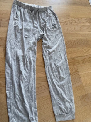 Grå mjuka loungewear-byxor med Bambi-tryck - Superbekväma grå loungewear-byxor i mjukt bomullsmaterial med resår och dragsko i midjan. Byxorna har sidofickor och ett gulligt tryck av Stampe från Bambi på ena benet. Perfekta för chill hemma eller mysiga dagar.