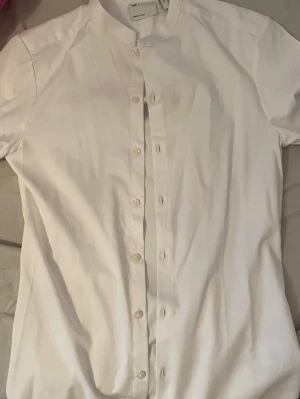ASOS kraglös vit skjorta - Vit kortärmad skjorta utan krage från ASOS. Storlek: 2xs men sitter som XS