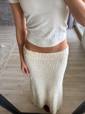 Vit stickad långkjol - Säljer en vit, stickad långkjol med grov struktur och bred resår i midjan. Perfekt till stranden, sitter mer som en s  💕