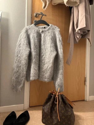 Ljusgrå fluffig stickad tröja Bik Bok - Supermjuk och fluffig ljusgrå stickad tröja från Bik Bok. Tröjan har rund halsringning, långa ärmar och en oversized passform. Perfekt för lager på lager och riktigt mysig känsla. Materialet innehåller mohair och ull för extra värme. Den är oanvänd🤍