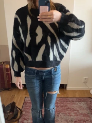 Svartvit zebramönstrad stickad tröja från Vila - Cool stickad tröja med zebramönster i svart och vitt. Tröjan har en croppad passform, rund hals och vida ärmar. Mjuk och fluffig kvalitet som känns skön mot huden. Perfekt för dig som vill sticka ut med ett trendigt mönster.