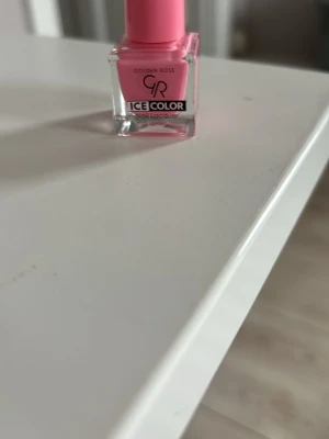 Golden Rose Ice Color rosa nagellack - Säljer ett snyggt rosa nagellack från Golden Rose Ice Color. Lacket kommer i en liten fyrkantig glasflaska med rosa plastlock och ger en jämn, pastellig finish på naglarna. Perfekt för dig som vill ha en fräsch och trendig look.