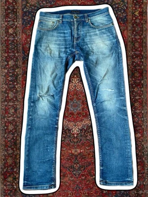  Nudie Jeans - Säljer ett par blå jeans från Nudie Jeans med slitningar . Skit snygga trendiga nudie jeans till ett grymt pris. Skriv om ni har frågor eller funderingar.