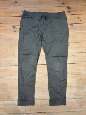 Black Diamond byxor - Snygga grå cargobyxor med elastisk midja och dragsko. Byxorna har flera fickor, resår vid benslut och är tillverkade i ett mjukt, lätt bomullsmaterial. Perfekta för en avslappnad och trendig stil.