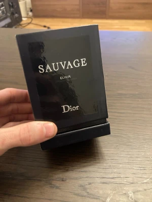 Dior Sauvage Elixir parfym - Dior Sauvage Elixir är en exklusiv herrparfym i en elegant mörkblå glasflaska med silverdetaljer. Flaskan har en rund form och kommer i en stilren svart kartong med silvertext. Doften är intensiv och maskulin, perfekt för dig som vill sticka ut. 100ml flaska näst intill aldrig använd! Frukstansvärt god doft.