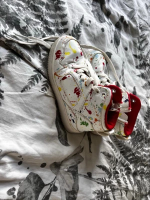 Vita sneakers, färgstänk, höga - Unika vita sneakers med färgstänk i rött, gult, grönt och blått. Skorna har högt skaft, vita snören och röd insida. Perfekta för dig som vill sticka ut med en kreativ och lekfull stil. Till Behandlad ovandel i syntetmaterial. Använd 2 gånger.