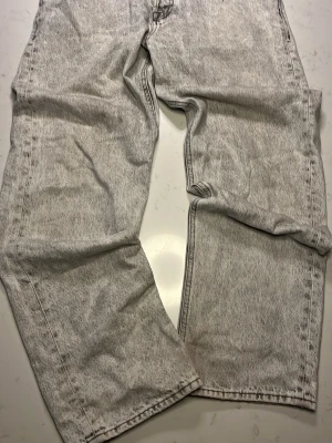 Ljusgråa loose fit jeans - S ‑äljer ett par ljusgråa loose fit jeans med stentvättad look. Jeansen har raka direct fit-ben och klassiska fem fickor. Perfekta för dig som gillar en avslappnad och trendig stil.