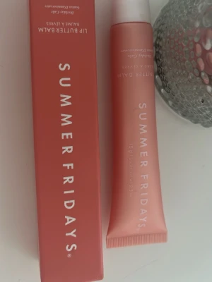 Summer Fridays Lip Butter Balm - Läppbalsam från Summer Fridays i en snygg persikorosa tub med vit kork. Tuben rymmer 15g och har en modern, minimalistisk design. Förpackningen är i plast och har tydlig vit text. Perfekt för att återfukta och vårda läpparna. endast testad fåtal gånger