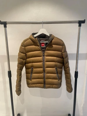 Colmar Jacka - Colmar jacka med huva och dragkedja framtill i fägren. Jackan har två sidofickor med dragkedja och quiltad design. Perfekt för kalla dagar. Materialet är lätt och ger bra värme. Storleken är i XS.