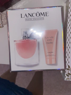 Lancôme La Vie Est Belle parfymset - Säljer ett exklusivt parfymset från Lancôme med doften La Vie Est Belle. Setet innehåller en elegant parfymflaska i glas med rosa innehåll och en matchande body lotion i rosa tub. Perfekt för dig som älskar fräscha och feminina dofter.