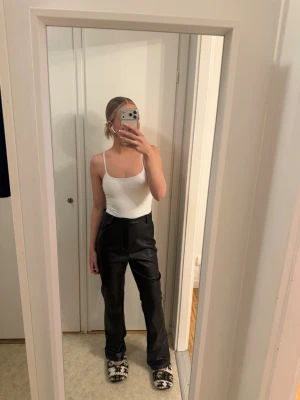 Svarta kostymbyxor i skinnimitation - Säljer ett par svarta kostymbyxor i skinnimitation från NAKD i storlek 36.(innerbenslängd 80cm och hela 109 cm. Byxorna är alldeles för stora för mig.