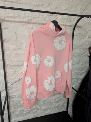 Rosa hoodie denim tears - Säljer en oversized rosa hoodie med stora vita molnliknande tryck över hela tröjan. Hoodien har huva och en stor magficka framtill. Perfekt för dig som gillar en classy stil