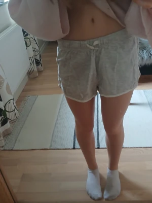 Grå mjuka shorts - Säljer ett par ljusgrå shorts i mjuk bomull med resårmidja och snörning framtill. Shortsen har en avslappnad passform och är perfekta för sommarens chill dagar. Enkla och stilrena utan mönster eller extra detaljer.