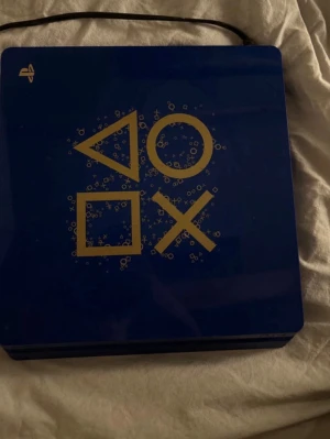 Blå PlayStation 4 ”Days of play” Limited Edition - Säljer en blå PlayStation 4 500 Million Limited Edition med guldfärgade PlayStation-symboler på ovansidan.  Medföljer en matchande blå kontroll med klassiska knappar och touchpad.              Ps4 använt i ≈5år.                                                                                                   .                                                                                Säljer för 1800kr men är villig att förhandla om priset!