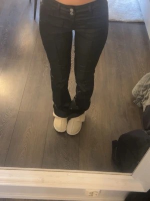 Svarta bootcut byxor med fickor - Säljer ett par svarta bootcut byxor med dubbla knappar och fickor framtill. 