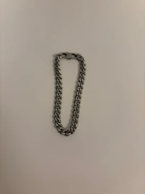 Kedjearmband i silverfärgad - Stilrent armband i silverfärgad med klassisk kedjedesign och robust lås. Perfekt för dig som gillar minimalistiska accessoarer med lite edge. Passar både ensam eller att kombinera med andra armband för en personlig stil. Armbandet är 19,5 cm långt. 