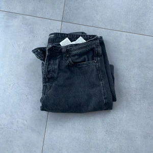 Svarta jeansbyxor - Snygga svarta jeansbyxor med en klassisk straight passform. De har en midwaist design och är perfekta för en avslappnad stil. Byxorna har en dragkedja och knappar framtill.