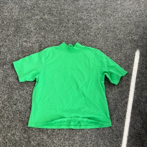 Grön t-shirt från Lindex - Säljer en grön t-shirt från Lindex i storlek M. Den har en enkel design med korta ärmar och rund hals. Perfekt för en avslappnad stil.