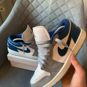 Nike Air Jordans i blått och grått - Snygga Nike Air Jordans i en fräsch kombination av blått, grått och vitt. Skorna har en klassisk design med snörning och en ikonisk logga på plösen. Perfekta för dig som vill ha en stilren look med en sportig touch.