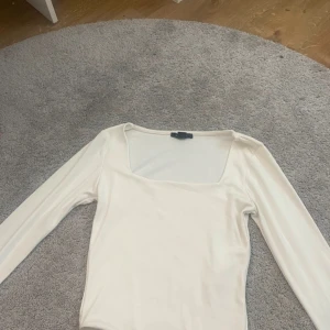 Vit långärmad topp från Amisu - Säljer en stilren vit långärmad topp från Amisu. Toppen har en fyrkantig halsringning och är perfekt för en minimalistisk look. Passar bra till både jeans och kjol. Perfekt för alla säsonger!