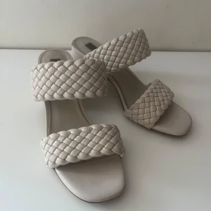 Beige flätade sandaler från Steve Madden - Snygga beige sandaler med flätade remmar och en låg klack. Använda en del, tagit bild på skavankerna. Sköna att gå i men tyvärr förstora.