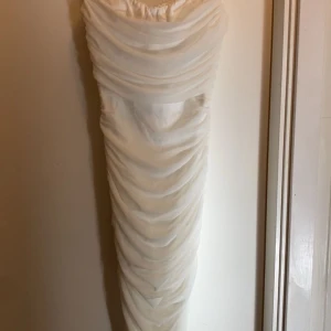 Vit omlottklänning med dragkedja - Elegant vit klänning med omlott-design och dragkedja i ryggen. Klänningen har en draperad stil som ger en snygg och sofistikerad look. Den är från Nelly i storlek XS